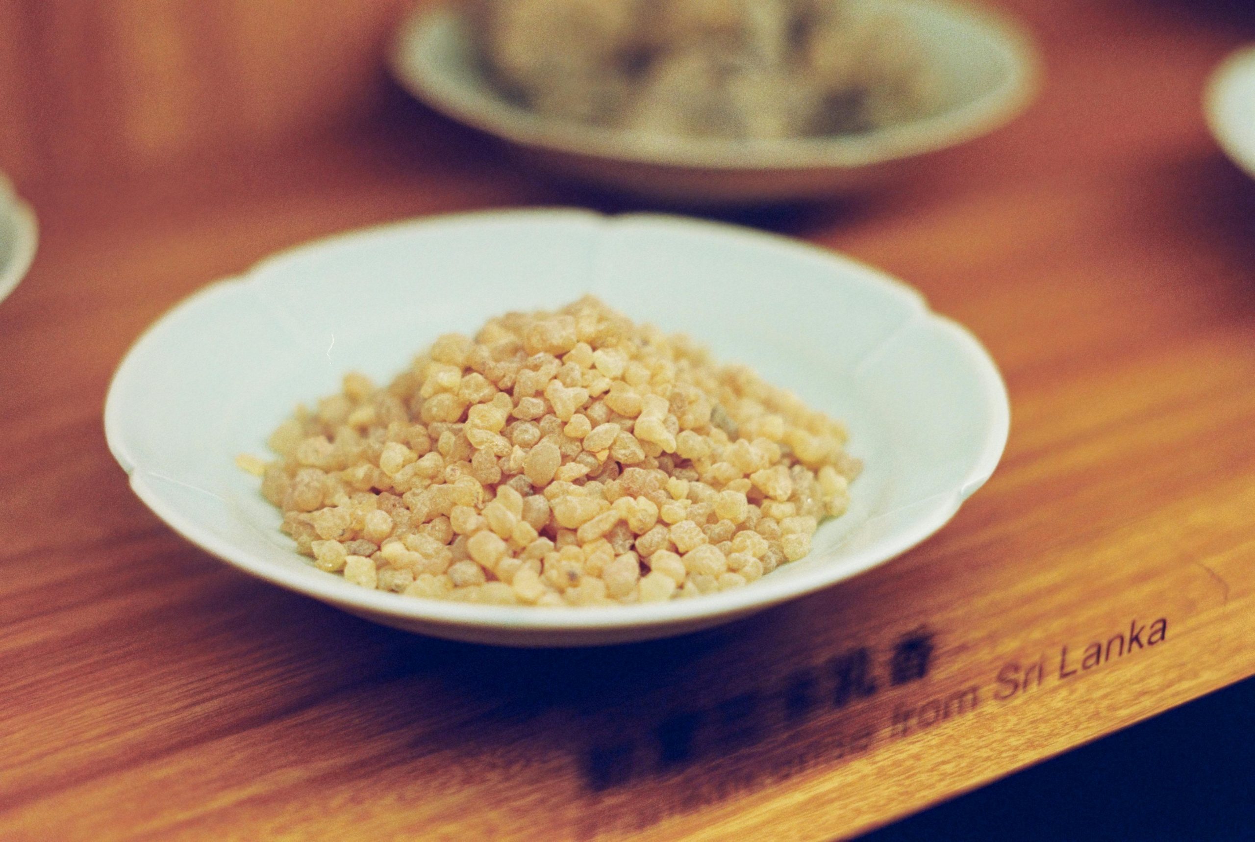 Close-up of natural frankincense resin from Sri Lanka in a white bowl on wooden surface.